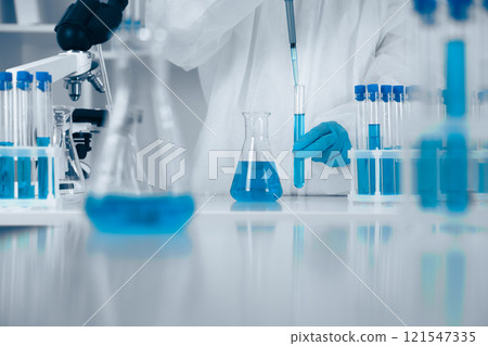 A dedicated scientist conducts experiments with blue solutions, demonstrating precision and innovation in biochemistry, microbiology, and healthcare, using beakers and flasks for safety A dedicated scientist conducts experiments with blue solutions, demonstrating precision and innovation in biochemistry, microbiology, and healthcare, using beakers and flasks for safety 121547335