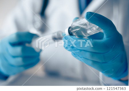 A qualified health professional prepares a vaccine with a sterile syringe and vial, ensuring safe immunization by following strict protocols prioritizing hygiene and patient safety 121547363