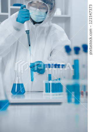 Laboratory Research Focus A Professional Scientist in Protective Gear, Diligently Conducts an Experiment Using a Pipette to Ensure Accuracy and Precision in Scientific Research and Innovation 121547373