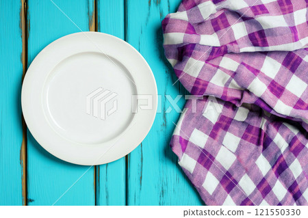 Elegant white plate on a colorful picnic tablecloth ready for a meal 121550330