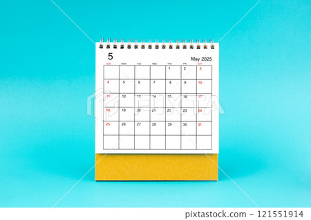 May 2025 desk calendar on blue background. 121551914