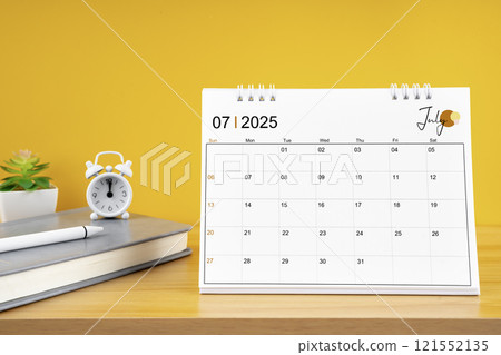 July desk calendar for 2025 year on work table with yellow. 121552135