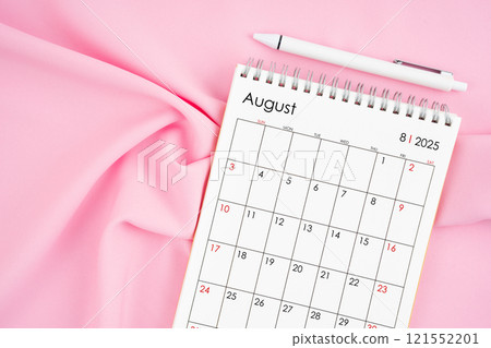 August 2025 month calendar and pen on pink fabric background. 121552201