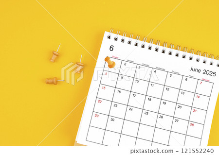 June 2025 Monthly desk calendar for 2025 year with wooden pin on yellow background. 121552240