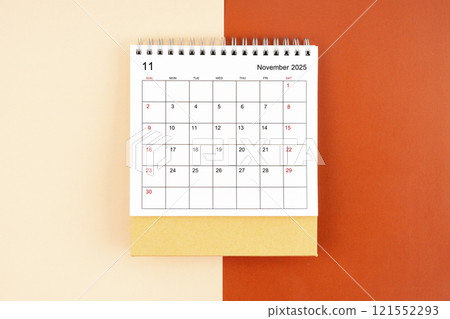 Directly above view of November 2025 desk calendar on orange background. Directly above view of November 2025 desk calendar on orange background. 121552293