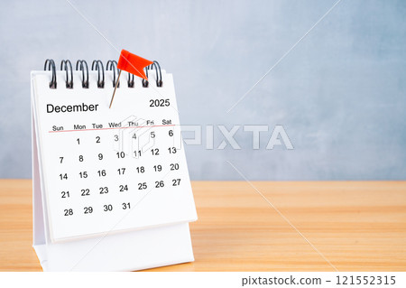 December 2025 calendar and red push pin on table. December 2025 calendar and red push pin on table. 121552315