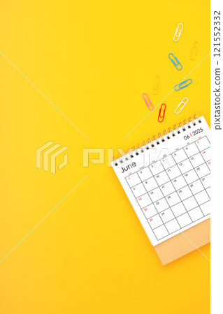 June 2025 desk calendar and paper clips on yellow background. Position with copy space. 121552332