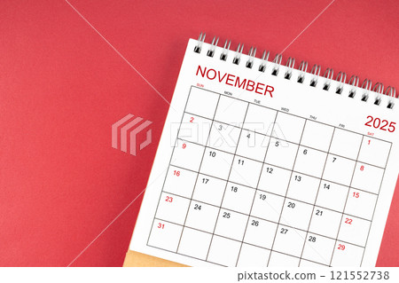 November 2025 desk calendar on red background. 121552738