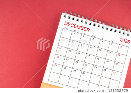 December 2025 desk calendar on red background. 121552779