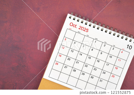 October 2025 desk calendar on red background. 121552875