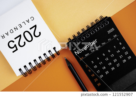 November 2025 desk calendar black and white color with pencil on orange background. 121552907