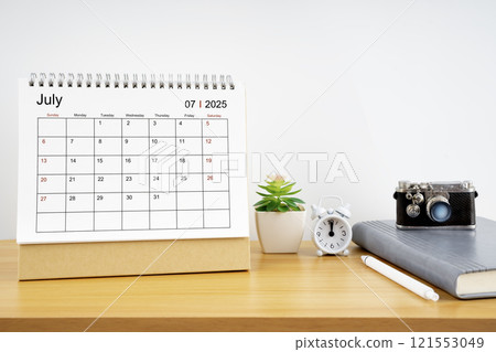 Desktop Calendar for July 2025 year and vintage camera with diary for Planner to plan timetable. 121553049