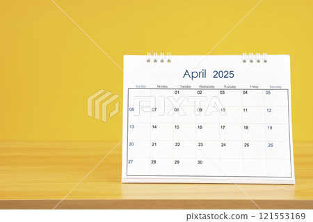 April 2025, Monthly desk calendar for 2025 year on wooden table on yellow background. 121553169