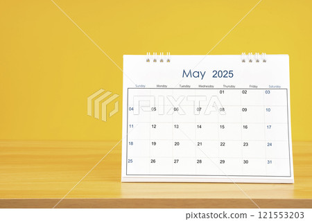 May 2025, Monthly desk calendar for 2025 year on wooden table on yellow background. 121553203