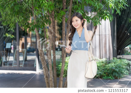 Businesswoman holding a tablet device in an office district Businesswoman holding a tablet device in an office district 121553317