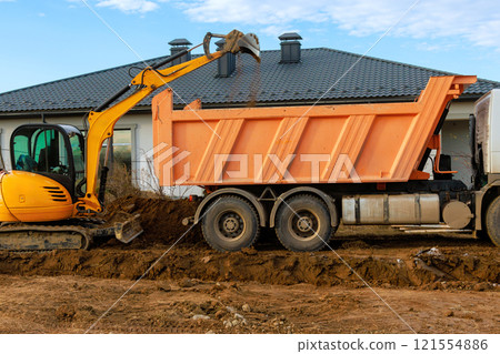 Construction workers are utilizing excavator to move soil into large dump truck for site preparation 121554886