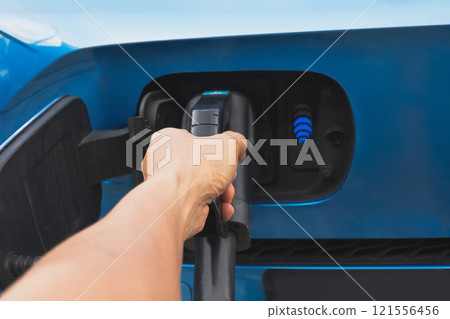 Closeup man hand charging electric car in station Closeup man hand charging electric car in station 121556456