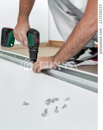 Caucasian male adult using drill to assemble metal frame with screws 121556523