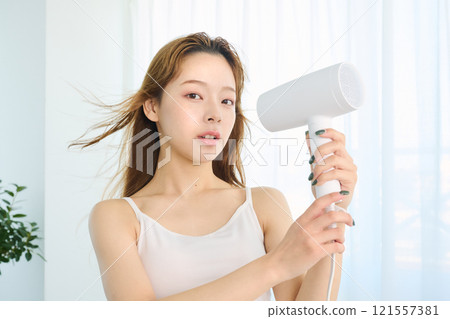 婦女用吹風機烘乾她的頭髮。 121557381