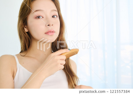 一個女人用梳子梳理頭髮 121557384
