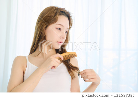 Woman combing her hair with a comb Woman combing her hair with a comb 121557385