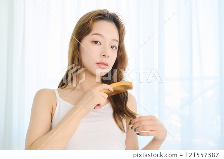 Woman combing her hair with a comb 121557387