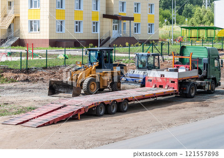 Truck with low loader, road roller and wheeled tractor on road repair Truck with low loader, road roller and wheeled tractor on road repair 121557898