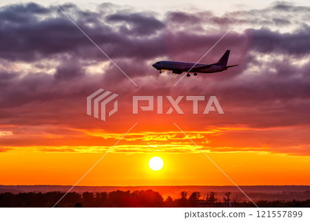 Early morning passenger airplane landing against the backdrop of a picturesque sunrise. Aircraft silhouette Early morning passenger airplane landing against the backdrop of a picturesque sunrise. Aircraft silhouette 121557899