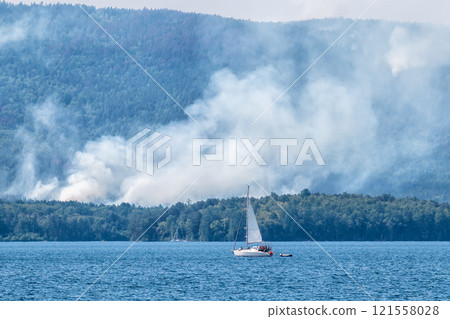 Forest fire near the lake 121558028
