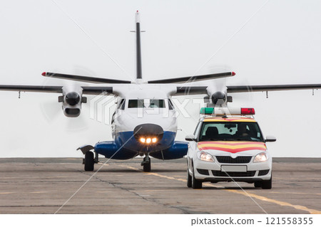 A small regional turboprop aircraft run the follow-me-car along the airport apron A small regional turboprop aircraft run the follow-me-car along the airport apron 121558355