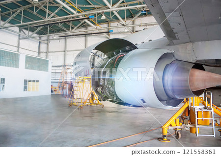 Close-up repair of aircraft engine on the wing. White airplane under maintenance in the hangar 121558361