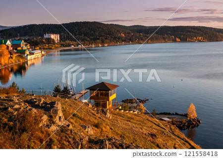 View of the bay of the picturesque lake from the rocky shore in the evening light in golden autumn 121558418