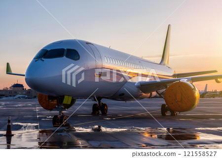 Modern passenger airplane on the airport apron against the backdrop of a scenic sunset Modern passenger airplane on the airport apron against the backdrop of a scenic sunset 121558527