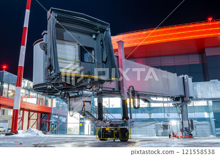 Empty passenger jet bridge at night airport apron 121558538