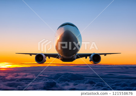 Front view of the wide body passenger aircraft fly in the sundown sky 121558676