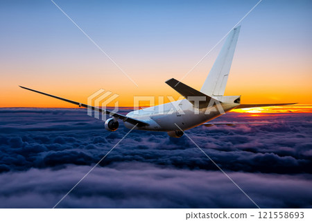 White wide body passenger airliner is flying in the sunset sky 121558693