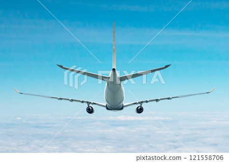 Rear view of a wide body passenger airplane flying in the air above the clouds 121558706