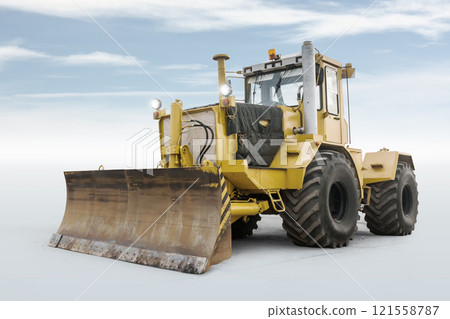 Yellow heavy wheeled tractor isolated on bright background with sky 121558787