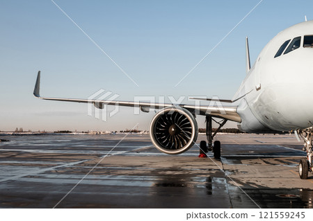 Front view of a white passenger airplane on an airport apron 121559245