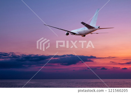 A large wide body passenger airplane takes off over the sea against the backdrop of a picturesque sunset sky A large wide body passenger airplane takes off over the sea against the backdrop of a picturesque sunset sky 121560205