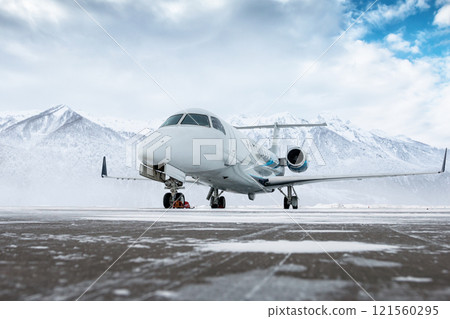 Luxury corporate business jet on the winter airport apron on the background of high scenic mountains 121560295