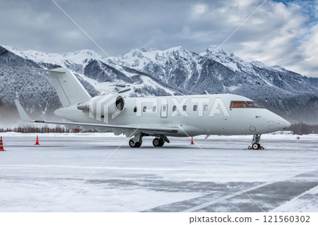 White luxury corporate business jet on the winter airport apron on the background of high scenic mountains 121560302