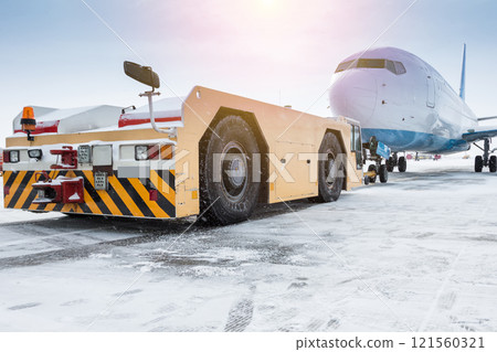Tow tractor pushes the passenger aircraft at the cold winter airport apron Tow tractor pushes the passenger aircraft at the cold winter airport apron 121560321