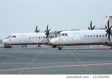 Two white passenger turboprop aircrafts on the airport apron Two white passenger turboprop aircrafts on the airport apron 121560489