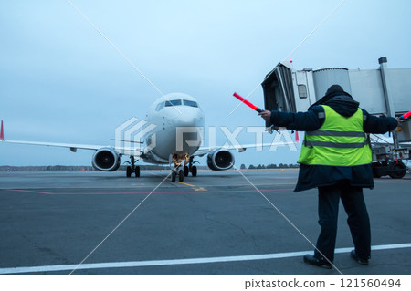 Aircraft marshalling at the aiport apron. Passenger airplane meeting Aircraft marshalling at the aiport apron. Passenger airplane meeting 121560494