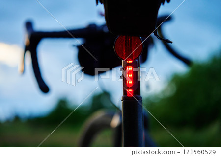 Glowing red bicycle tail light in twilight Glowing red bicycle tail light in twilight 121560529