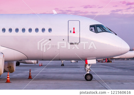 Front part of white modern passenger airliner on the morning airport apron 121560616