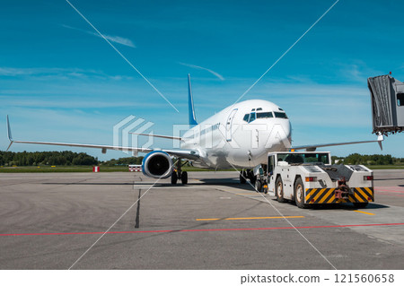 Tow truck pushes the passenger aircraft away from the boarding bridge 121560658