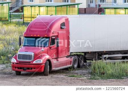 Red long-distance bonnet truck with a white semitrailer in the countryside Red long-distance bonnet truck with a white semitrailer in the countryside 121560724