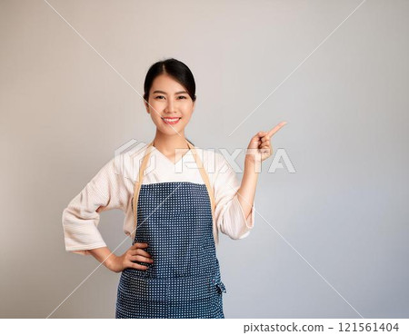 一個穿著圍裙的漂亮女人指著旁邊 一個穿著圍裙的漂亮女人指著旁邊 121561404
